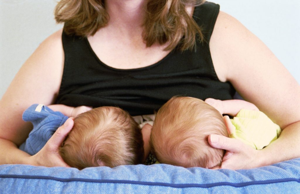 Mother breastfeeding twin baby boys (3-6 months), mid section
