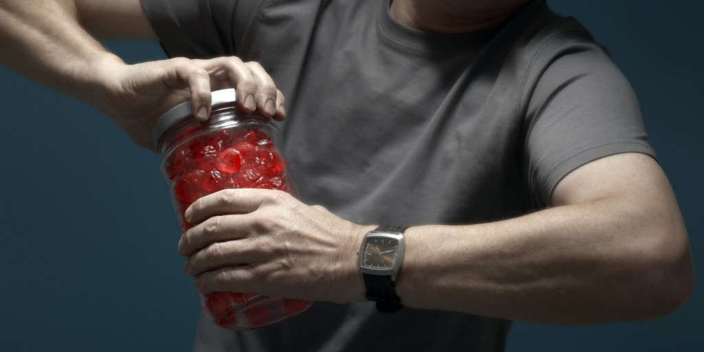 Mature man opening jar of candies, mid section (focus on hands)